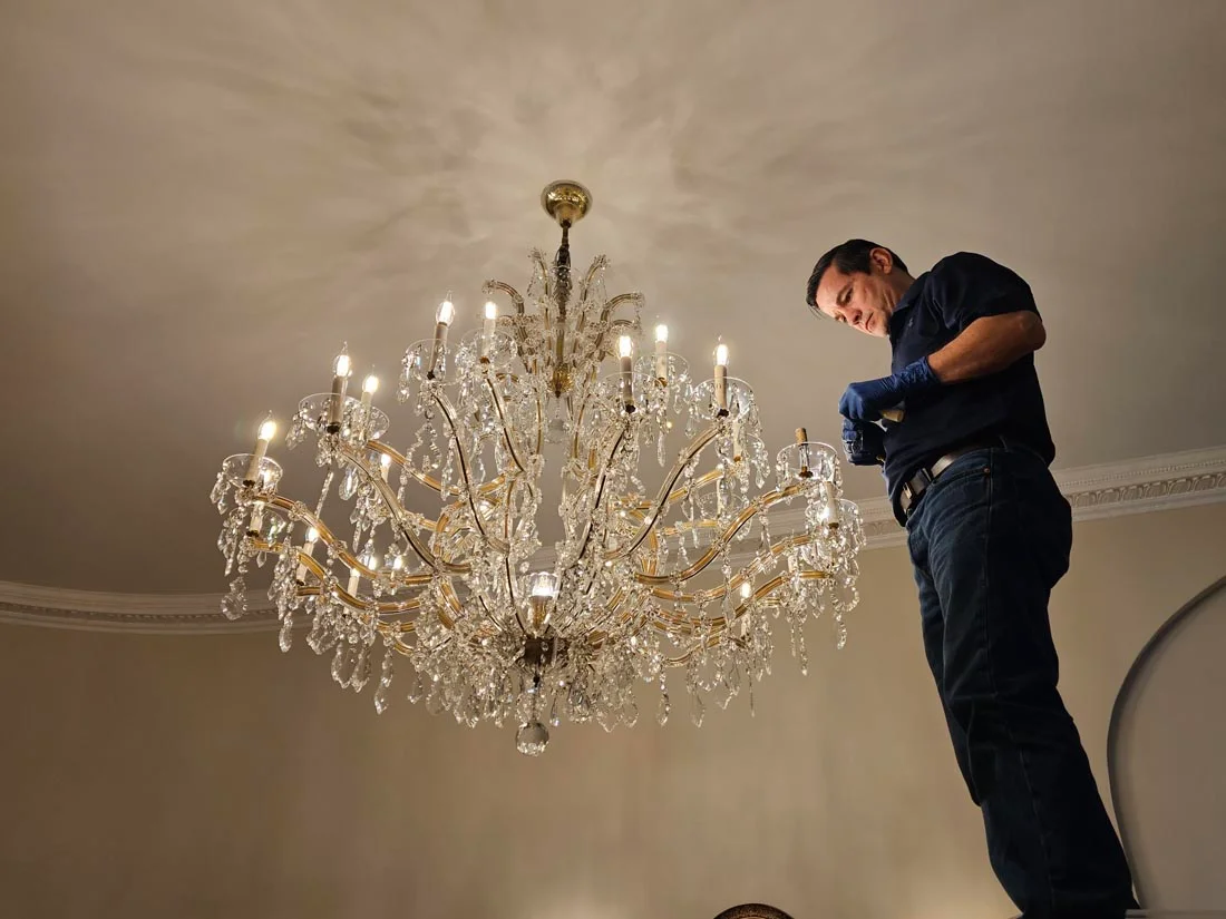 andres londono working on chandelier on ladder
